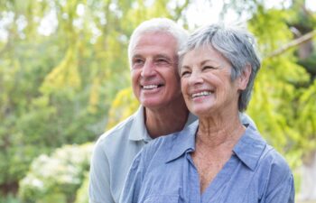 Happy old couple smiling in a park on a sunny day